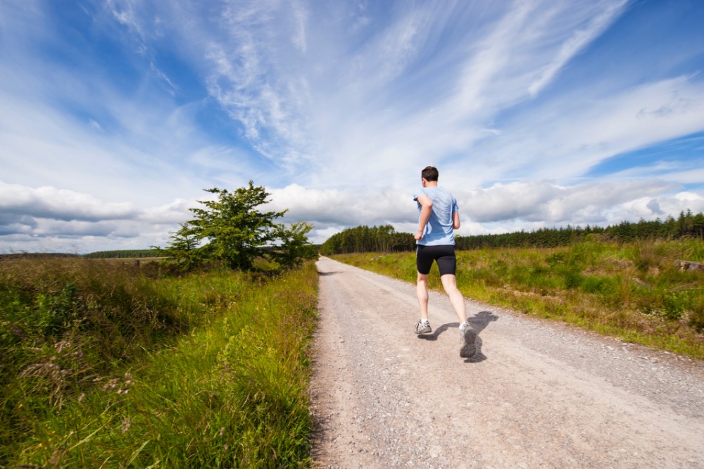 A man jogging on a rugged road.