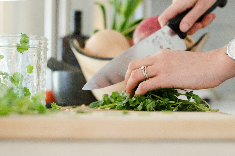 A person skillfully chopping herbs on a cutting board.