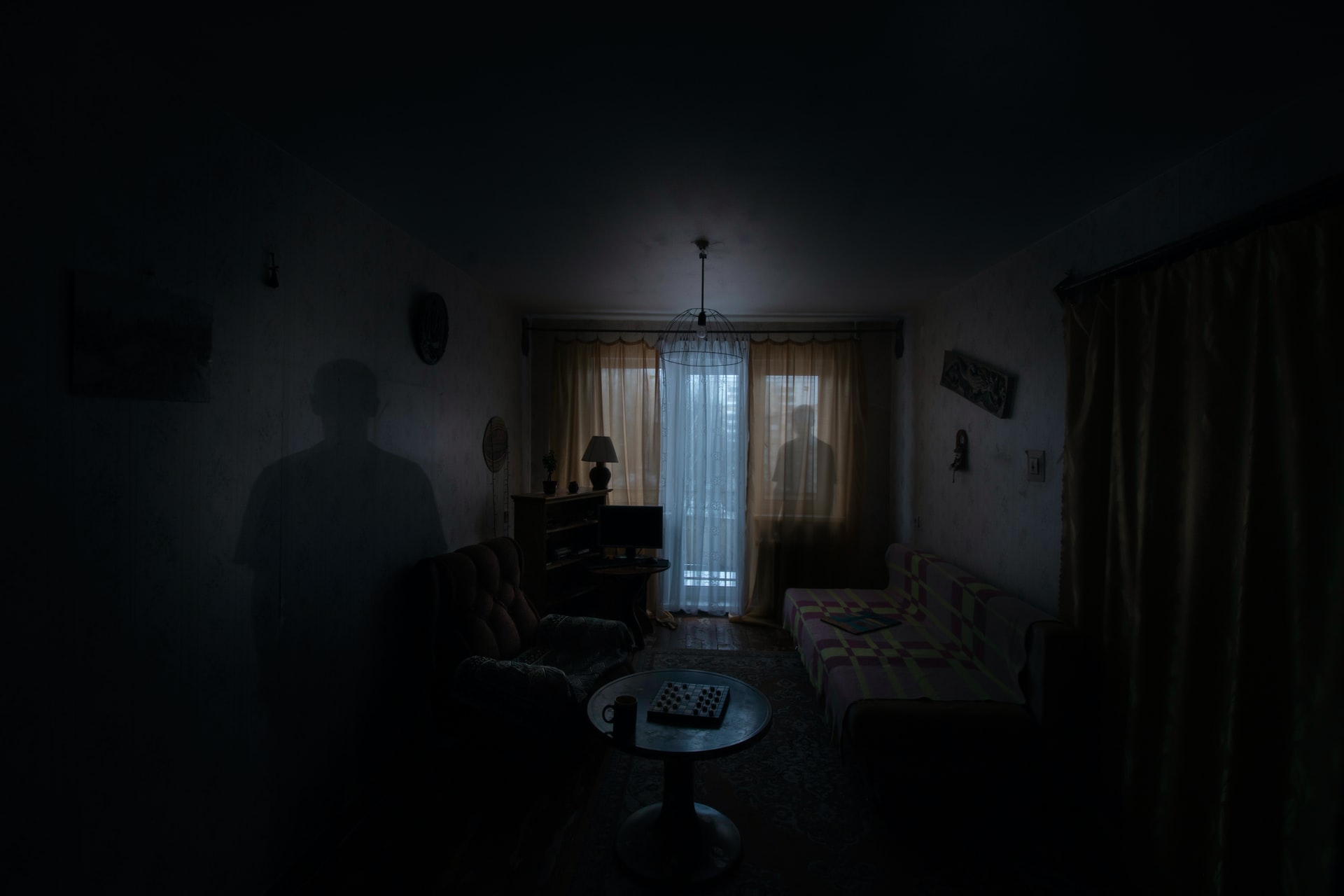 A dark living room with eerie silhouettes.