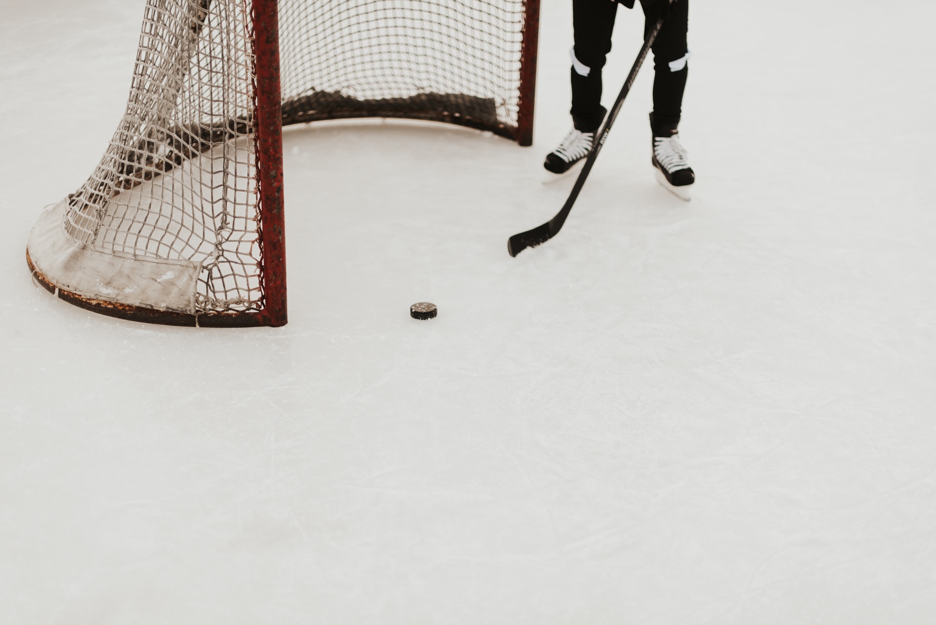 A person standing next to a hockey goal on the ice rink.
