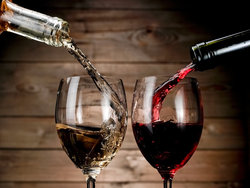 Two glasses being filled with wines.