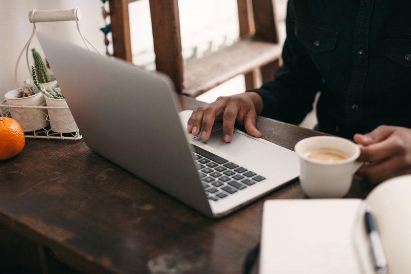 Person with a cup of coffee and working on a laptop.