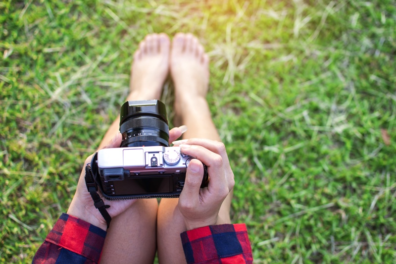 A person holding a camera in the grass.