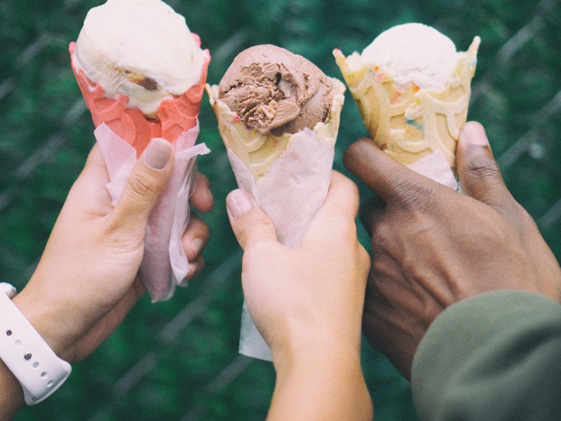 Three hands each holding an ice cream on a cone.