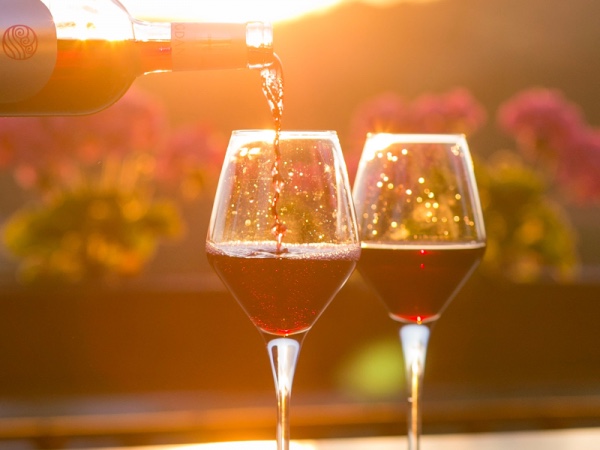 Two glasses being filled with red wine.