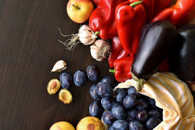 Assorted fruits and veggies on table: apples, oranges, carrots, and more.