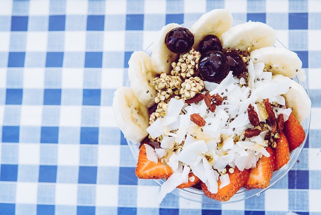 A delicious dessert bowl with strawberries, nuts, blueberries, banana slices.