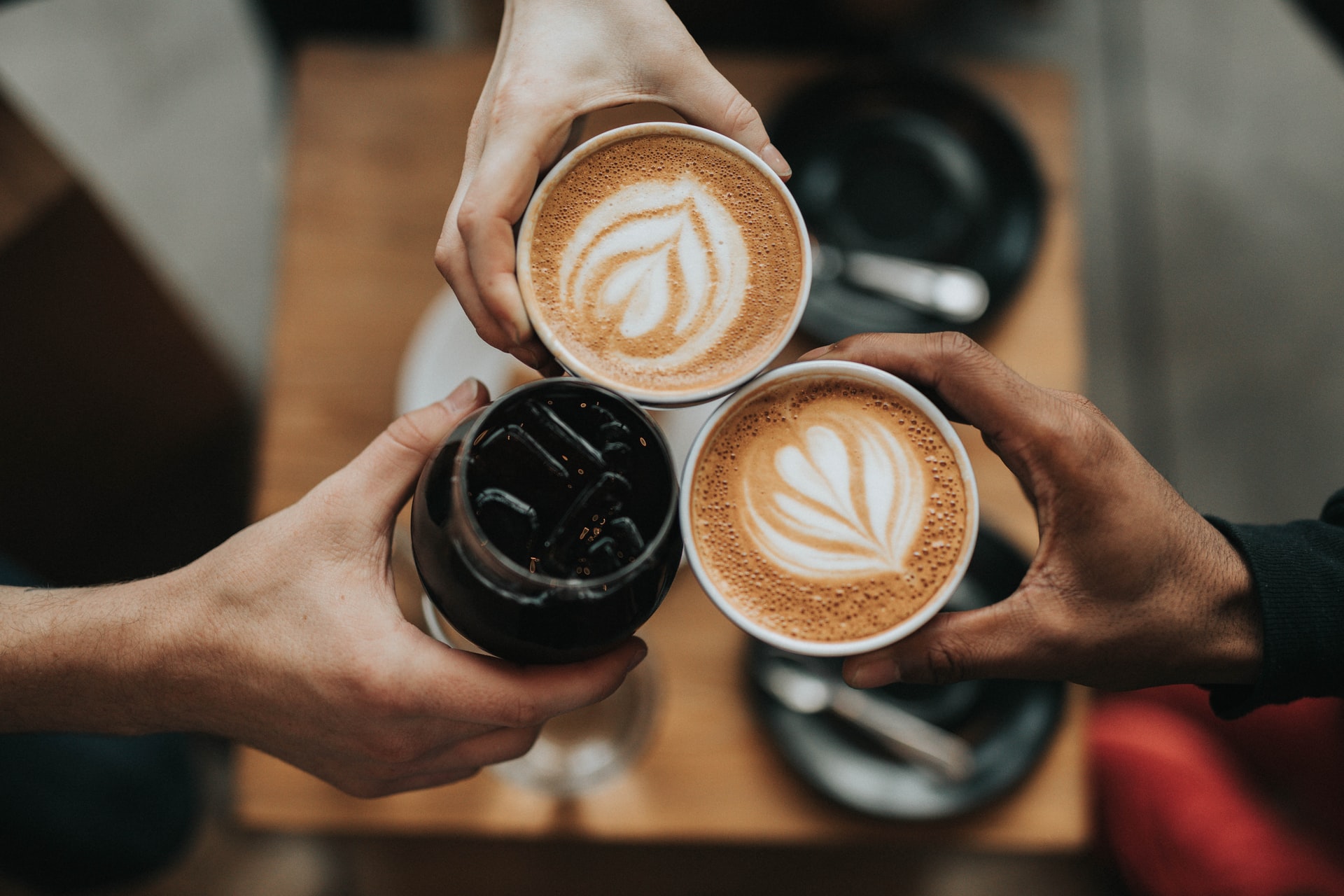 Top shot of people holding coffee cups and wine glass.