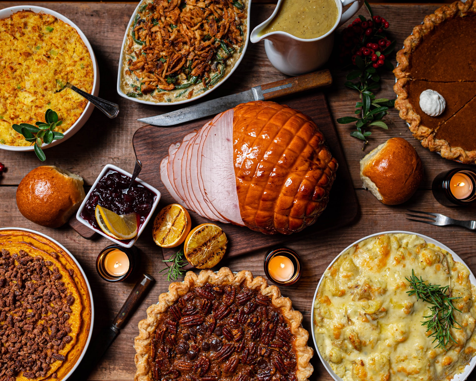 A wooden table with ham, pies, and other sumptuous food.