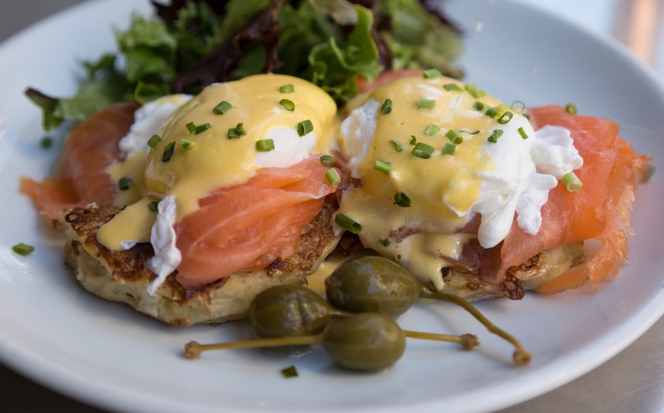 A delicious plate of eggs benedict on top of salmon.