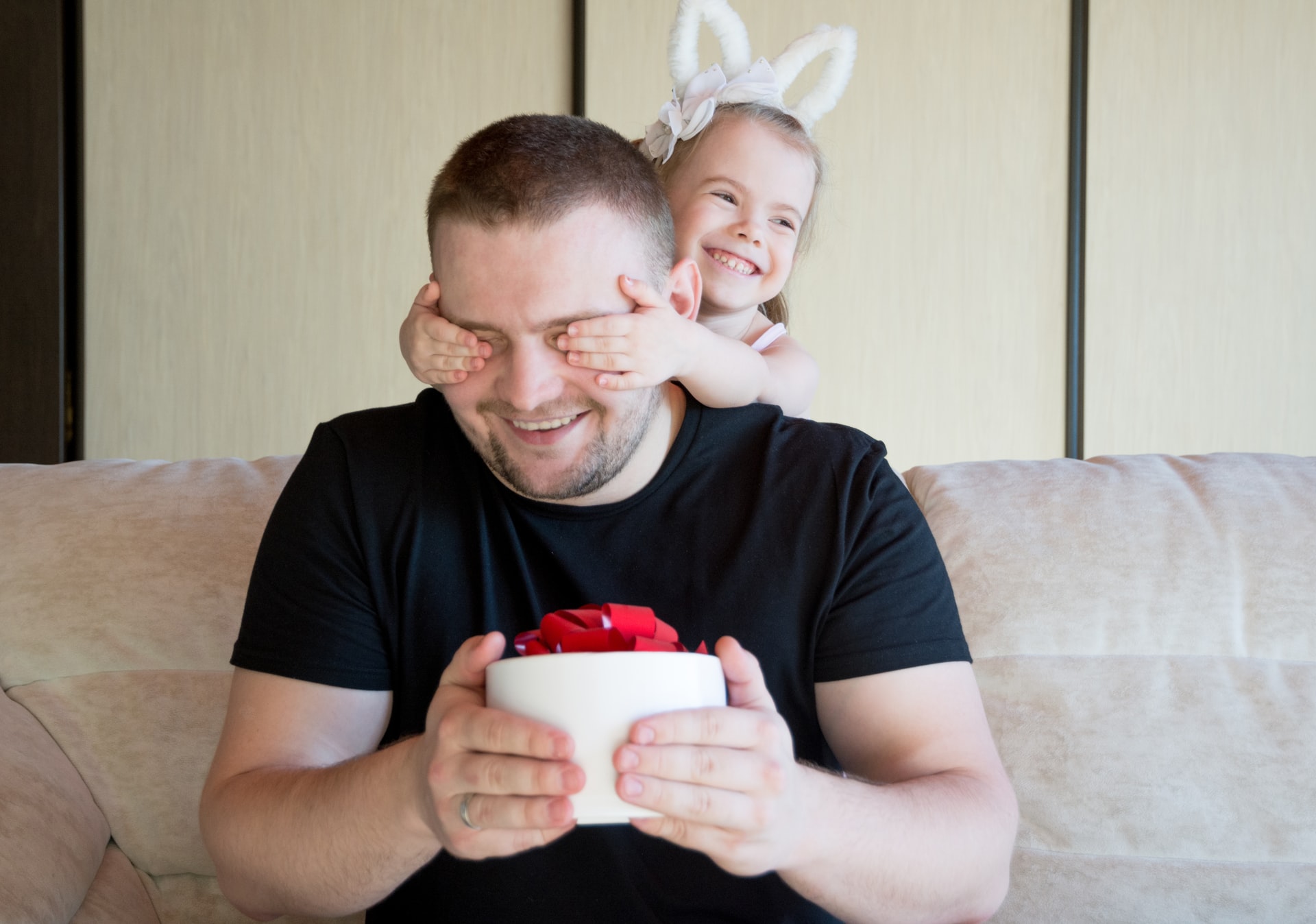 A joyful dad and his daughter playing on the sofa at home.