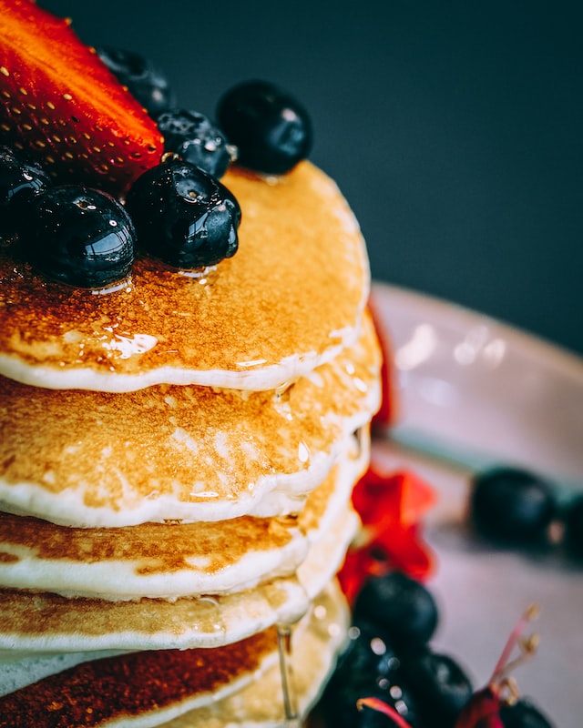 Closeup of pancake with fruit toppings and syrup.
