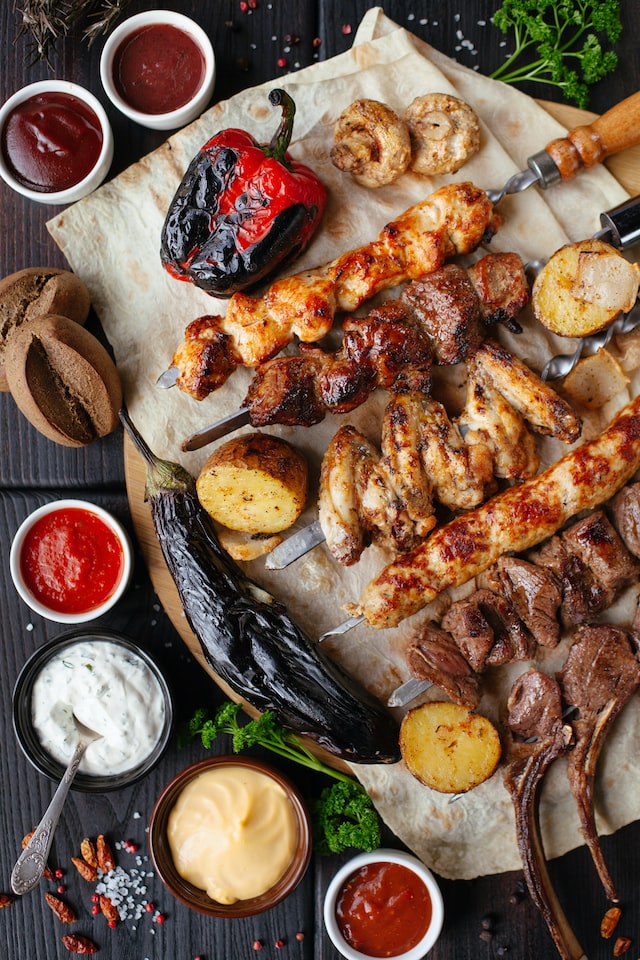Assorted grilled meat and vegetables on wooden table.