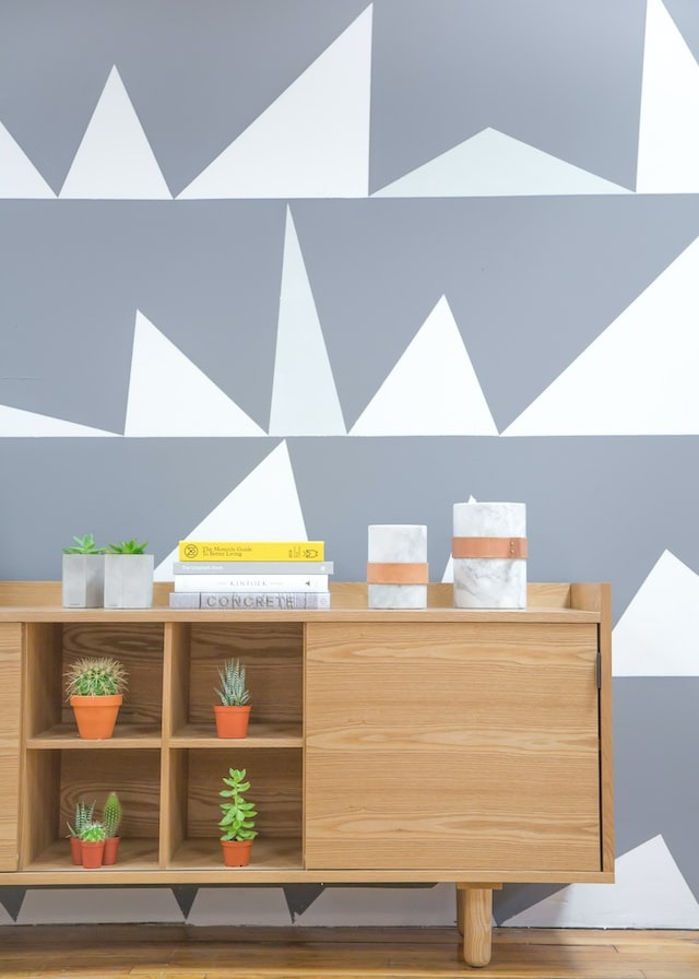 Wooden shelf with succulents amidst a simply decorated wall.